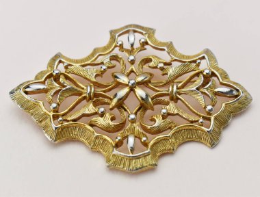 Beyaz arkaplanda altın broş, fotoğrafın yakın çekimi.