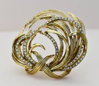 Beyaz arkaplanda elmaslı altın broş, yakın plan..