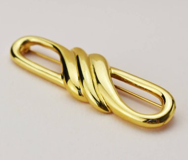 Beyaz zemin üzerinde altın bir broş yakın, sığ bir alan derinliği