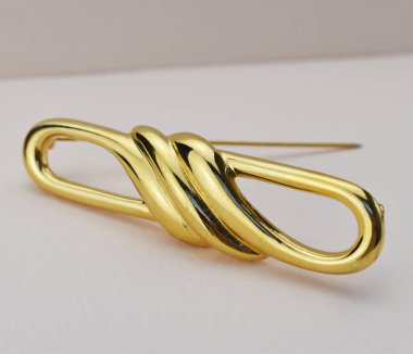 Beyaz arka planda altın bir broşun yakın çekimi, stüdyo çekimi.