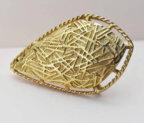 Beyaz arkaplanda altın broş, fotoğrafın yakın çekimi.