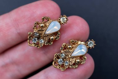 Koyu arkaplanda elinde takılar var. Yakın plan.