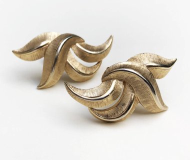 Beyaz arkaplanda bir çift altın küpeye yakın plan