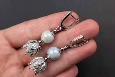 Siyah zemin üzerinde turkuaz taşlar olan gümüş küpeler.