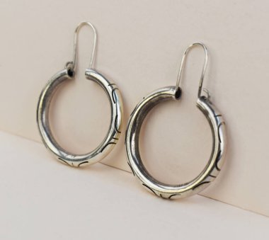 Bej arka planda gümüş küpeler. Mücevher arkaplanı.