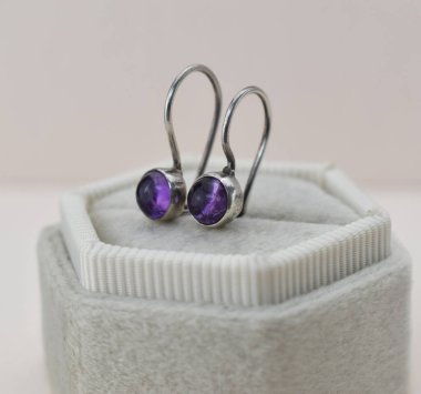 Kutusunda mor değerli taşlar olan bir çift gümüş küpe.