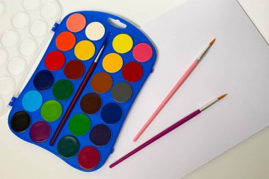 Beyaz arka planda suluboya resimler ve fırçalar. Okula geri dön..