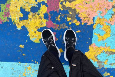 Calvin Klein marka spor ayakkabılı kadın bacakları rengarenk döşeme boyasının arka planında