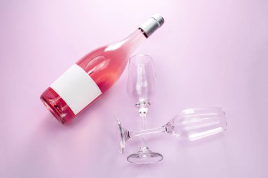 Bir şişe gül şarabı ve iki bardak pembe arka plan, üst manzara.