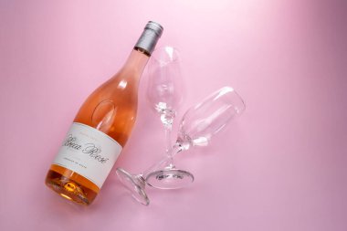 Şarap şişesi ve pembe arka planda iki bardak. Üst görünüm.