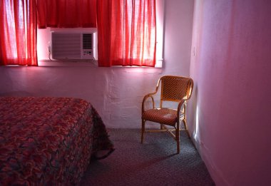 Ön planda hasır bir sandalye olan bir otel odası.