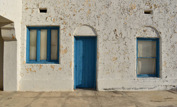 Two blue doors in the white wall of an old house in Tunisia