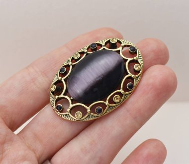 Elinde ametist olan gri arka planda mücevher broşu.