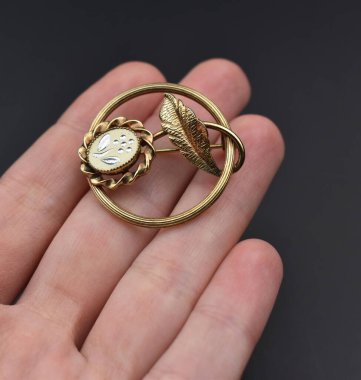 Elindeki altın broş siyah arka planda izole edilmiş. Mücevher ve aksesuarlar..