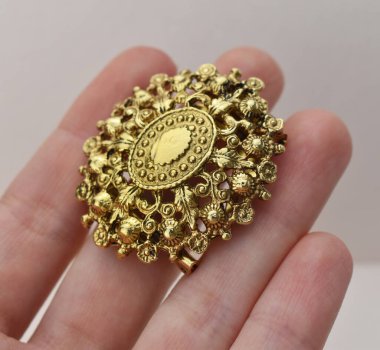 Elinde çiçek şeklinde altın bir broş vardı..