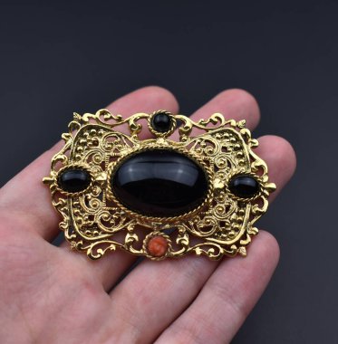 Siyah arka planda güzel altın bir broş. Yakın plan.