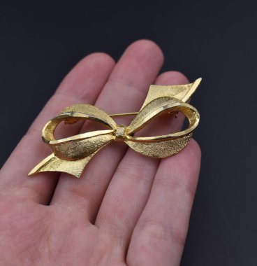 Beyaz arka planda altın bir kurdele tutuyor. Kapat..