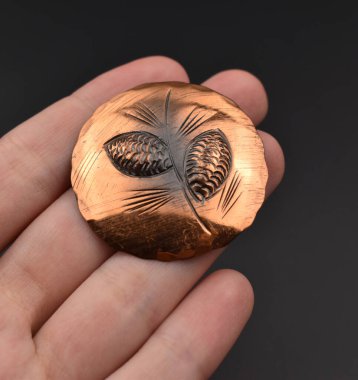 Eldeki altın broş siyah arkaplanda izole edilmiş. 