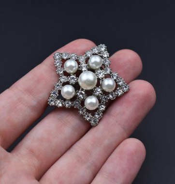 Elinde inciler olan gümüş bir broş..