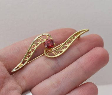 Beyaz arka planda kırmızı yakutlu altın broş. Mücevher konsepti