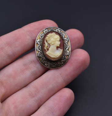 Elinde gümüş bir madalyon var. 