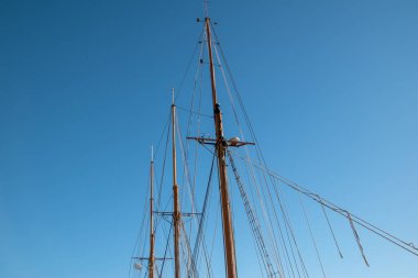 Mavi gökyüzüne karşı yelkenli bir yatın direkleri ve donanımları.