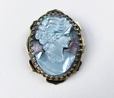 Beyaz arka planda Bakire Meryem resmi olan bronz bir broş.