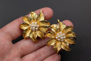 Siyah arka planda incileri olan altın küpeler..