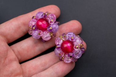 Elinde pembe ve mor taşlı bir çift küpe var.