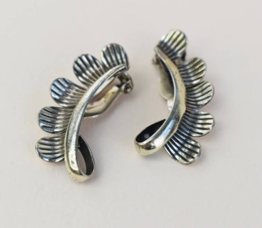 Beyaz arkaplanda bir çift gümüş küpenin yakın çekimi