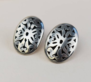 Beyaz arka planda iki gümüş küpeye yakın plan.