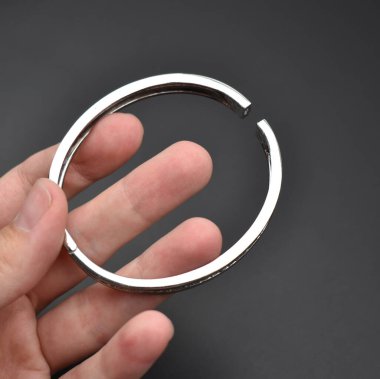 Metal bir bileziği tutan el. Siyah bir arkaplanda izole edilmiş.