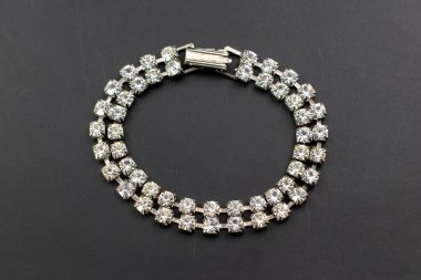 Silver bracelet with diamonds on a black background. Flat lay, top view.