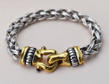 Gri arka planda gümüş ve altından bilezik..