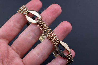 Siyah arka planda altın bir zincir tutan bir el. Kapat..