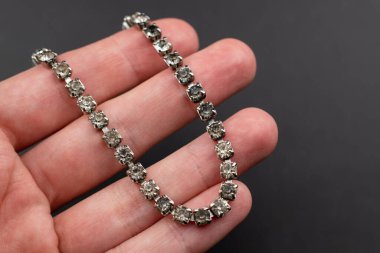 Siyah arka planda, elinde bilezik var.