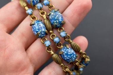 Koyu arkaplanda mavi ve sarı taşlar olan el ele tutuşan bilezik..