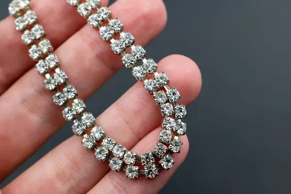 Jewelry diamond bracelet in hand on a dark background close up