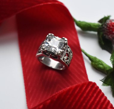 Beyaz arka planda kırmızı kurdeleli alyans..