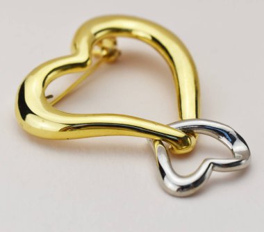 Beyaz arkaplanda kalp şeklinde broş, yakın plan.