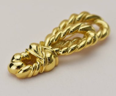 Beyaz arka planda altından yapılmış bir broş.