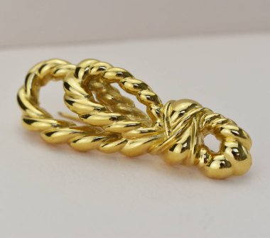 Beyaz arka planda altından yapılmış bir broş.