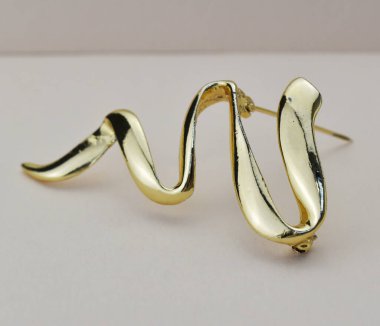 Hafif arka planda altın broş. Mücevher ve aksesuarlar..