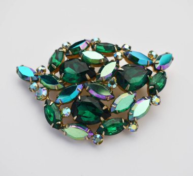 Beyaz arkaplanda yeşil zümrüt olan mücevher broşu