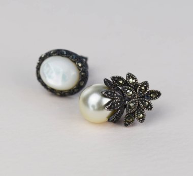 Beyaz arka planda siyah beyaz inci küpeler.