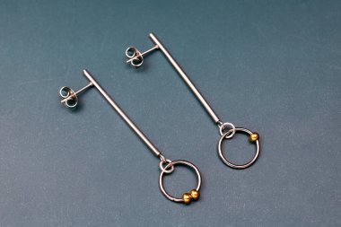 Koyu arkaplanda metal küpeler. Mücevherler, aksesuarlar.