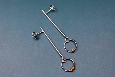 Koyu arkaplanda metal küpeler. Kadınlar için moda aksesuarlar