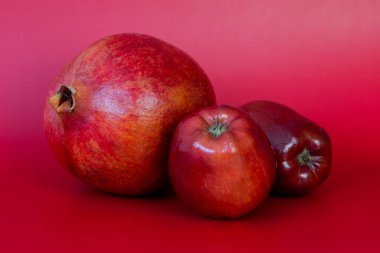 Kırmızı zemin üzerinde olgun nar ve elmalar.