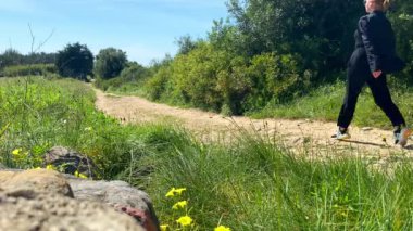 Güneşli bir günde doğada yürüyen beyaz bir kadın.