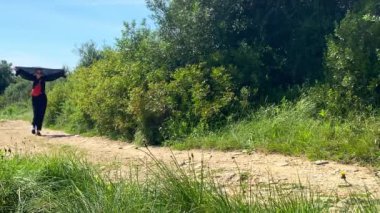 Güneşli bir günde doğada yürüyen beyaz bir kadın.